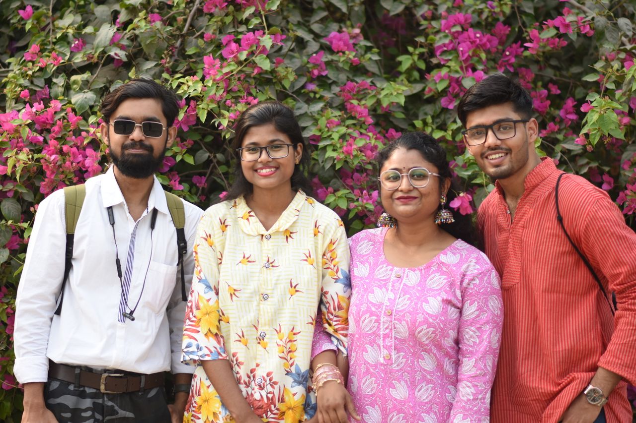 A cheerful group of friends posing in front of vibrant bougainvillea flowers, showcasing ethnic fashion styles.