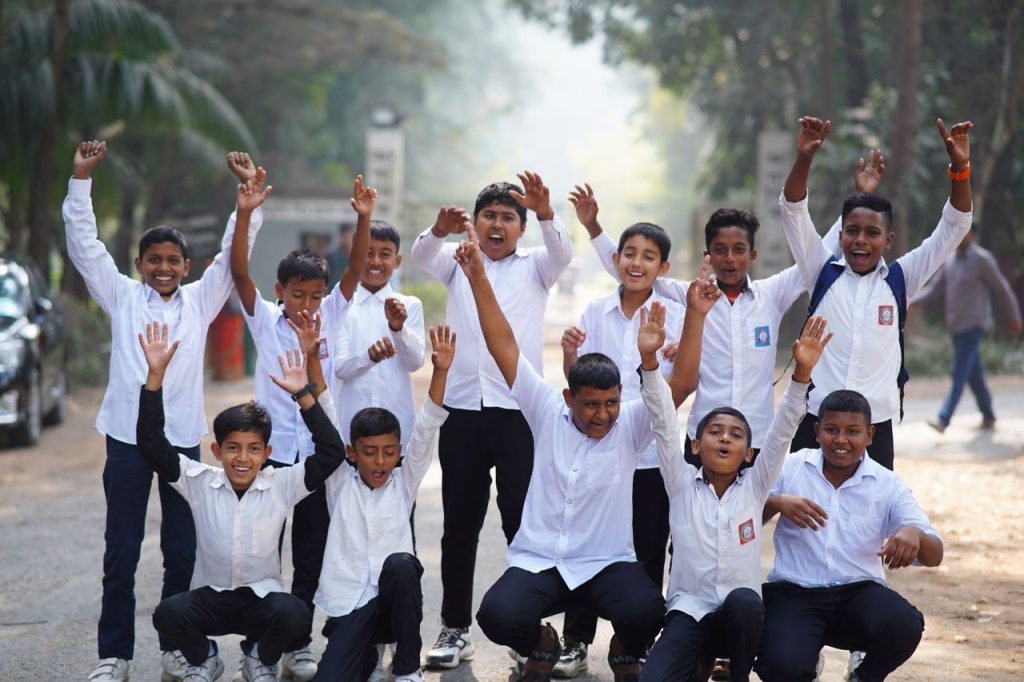 Energetic group of school boys in uniform celebrating outdoors in Bangladesh.